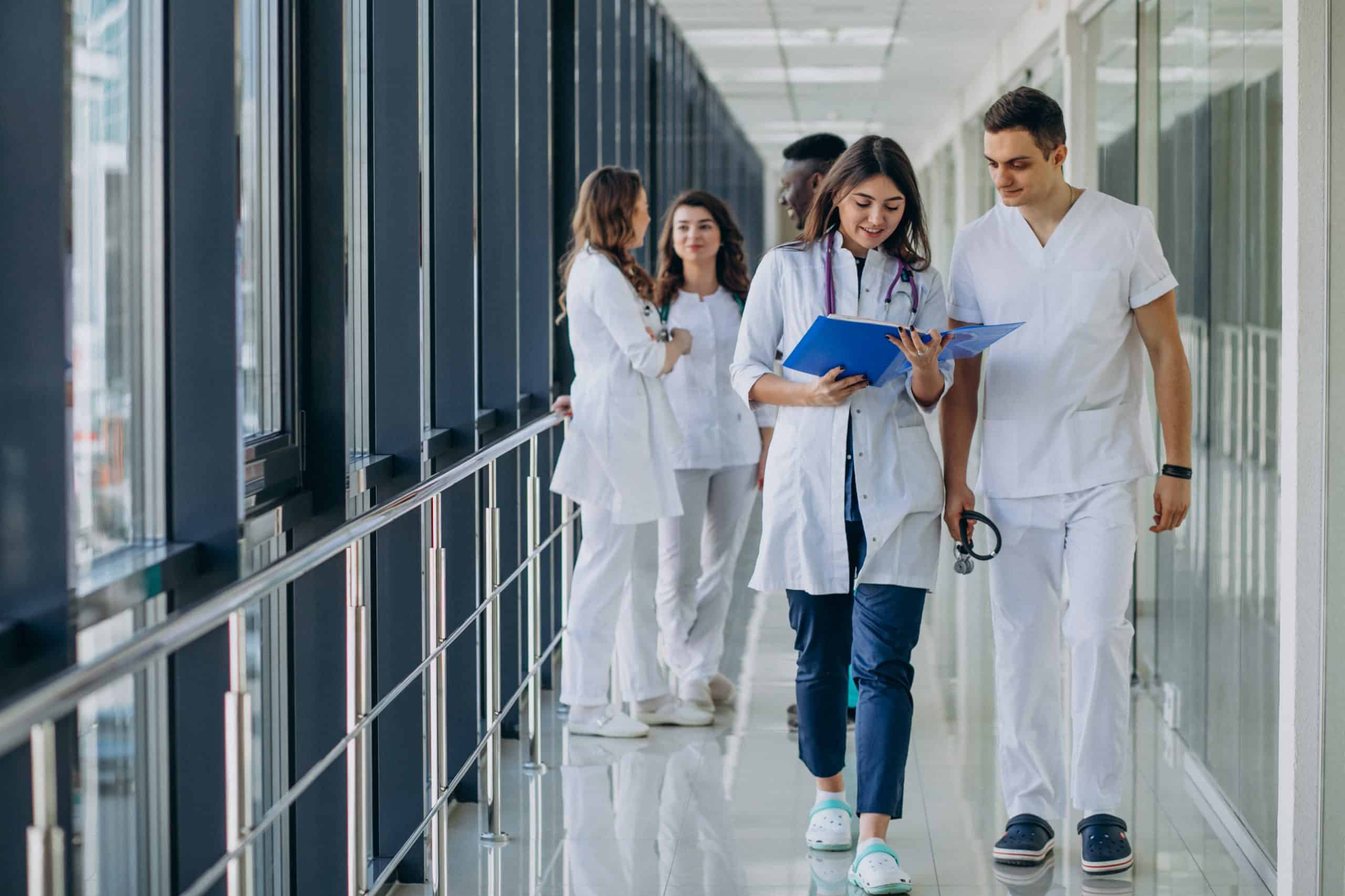 Time de médicos jovens andam pelo corredor de hospital