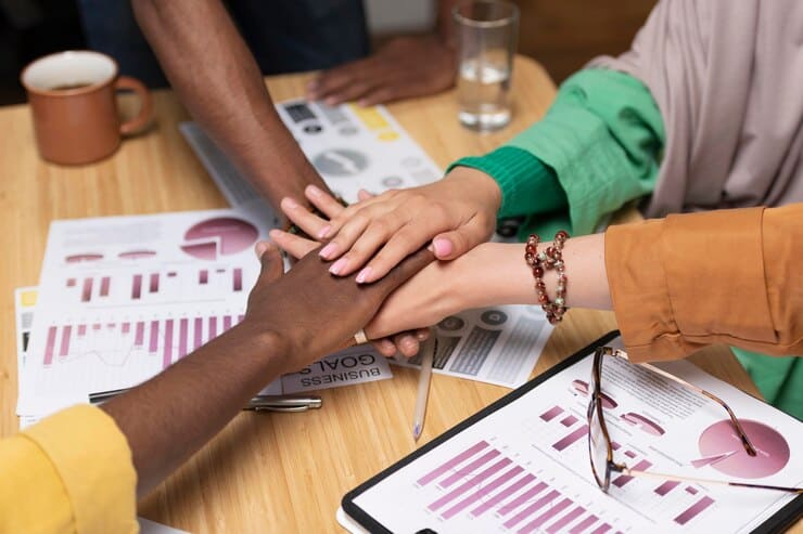 Colaboradores de mãos dadas durante uma reunião da empresa.